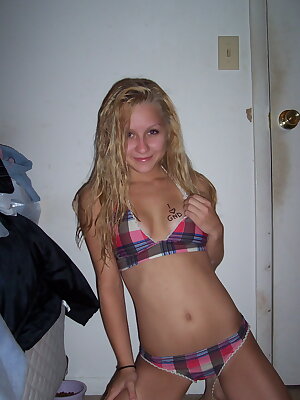 a woman in a plaid bikini posing for a picture in a room with a door open and a bed in front of her and a closet in the background and a door behind her and a door behind her