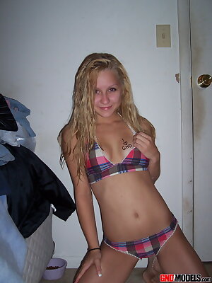 a woman in a plaid bikini posing for a picture in a room with a door open and a bed in front of her and a closet in the background and a door behind her and a door behind her